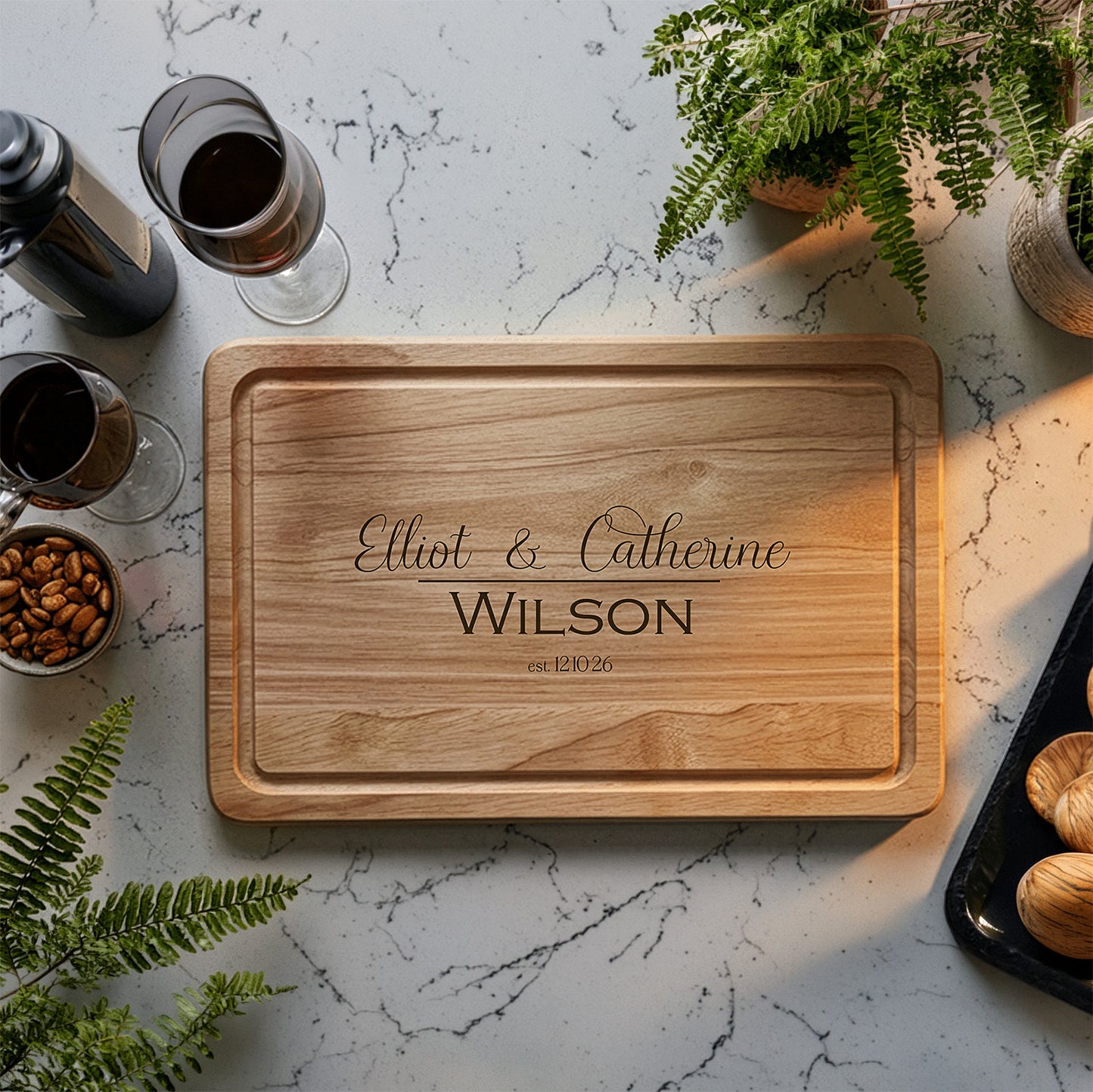 Personalised wedding chopping board with engraved names on a marble surface with wine glasses and snacks.