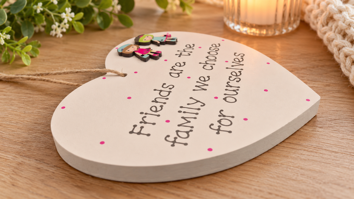 Close-up of the Friends are the family we choose wooden heart plaque displayed on a warm wooden tabletop