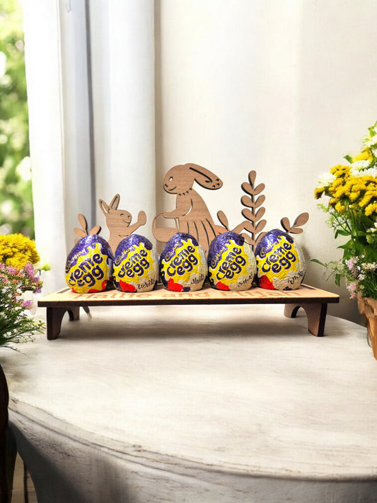 Easter display stand with Cadbury Creme Eggs and festive wooden cutouts on a decorative wooden base.