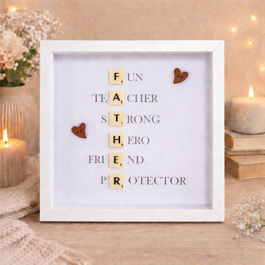 Framed artwork with Scrabble tile letters spelling out FATHER and a message definition of father on a wooden surface.