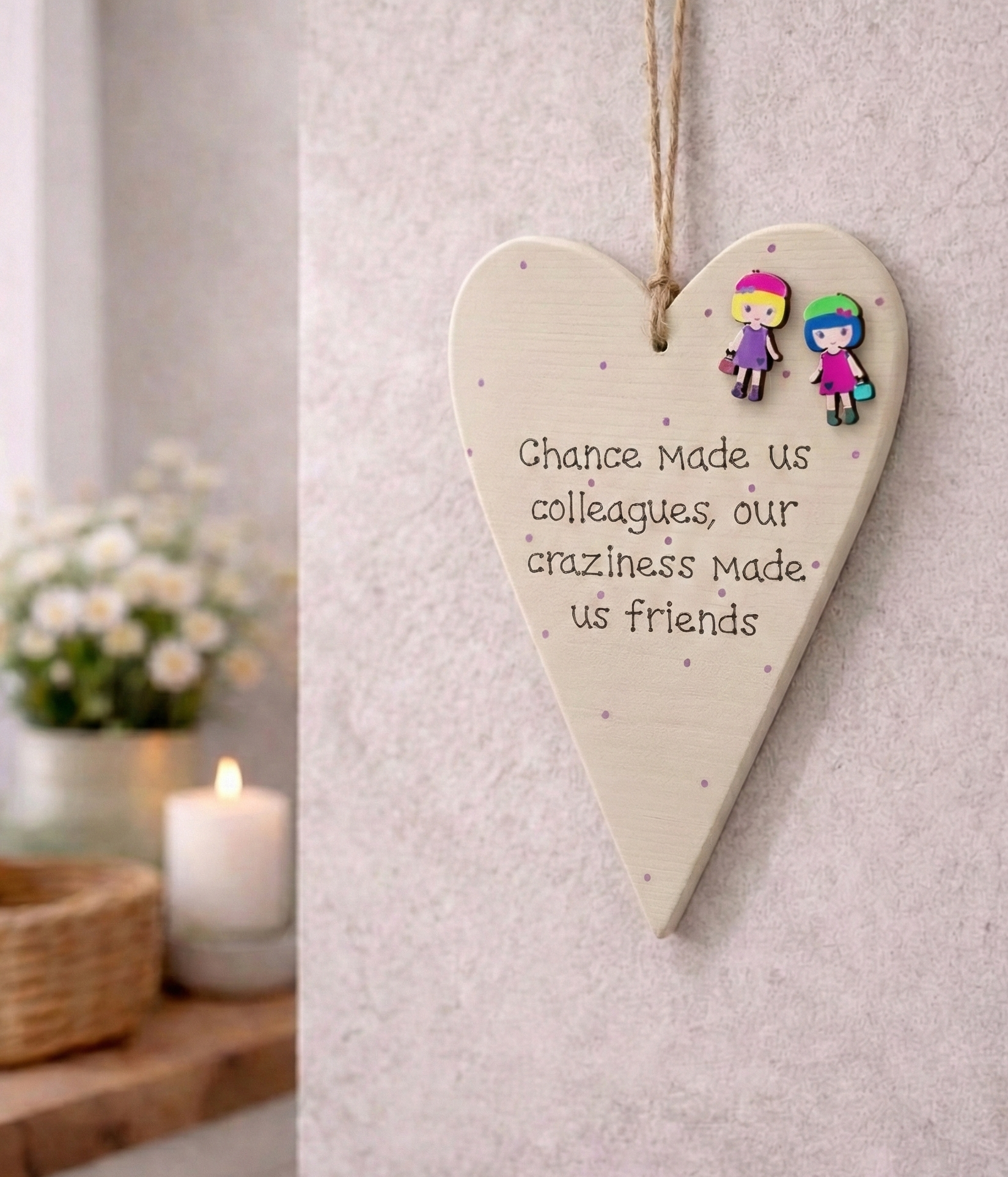 Heart-shaped , beige painted wooden plaque with text  chance made us colleagues our craziness made us friends and illustrations of 2 brightly coloured girls on a wall.