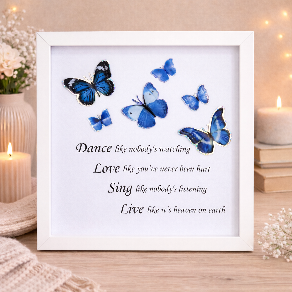 Framed print with blue butterflies and inspirational quotes on a wooden surface with candles and flowers.