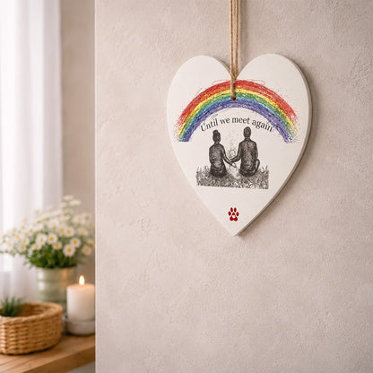Heart-shaped decorative memorial dog plaque with a rainbow and two people sitting together with their dog who has passed