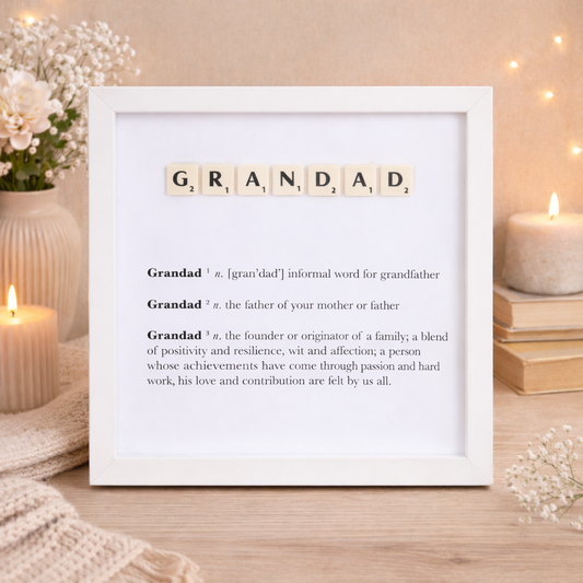 Framed definition of 'Grandad' in scrabble letters  with decorative elements on a wooden surface.