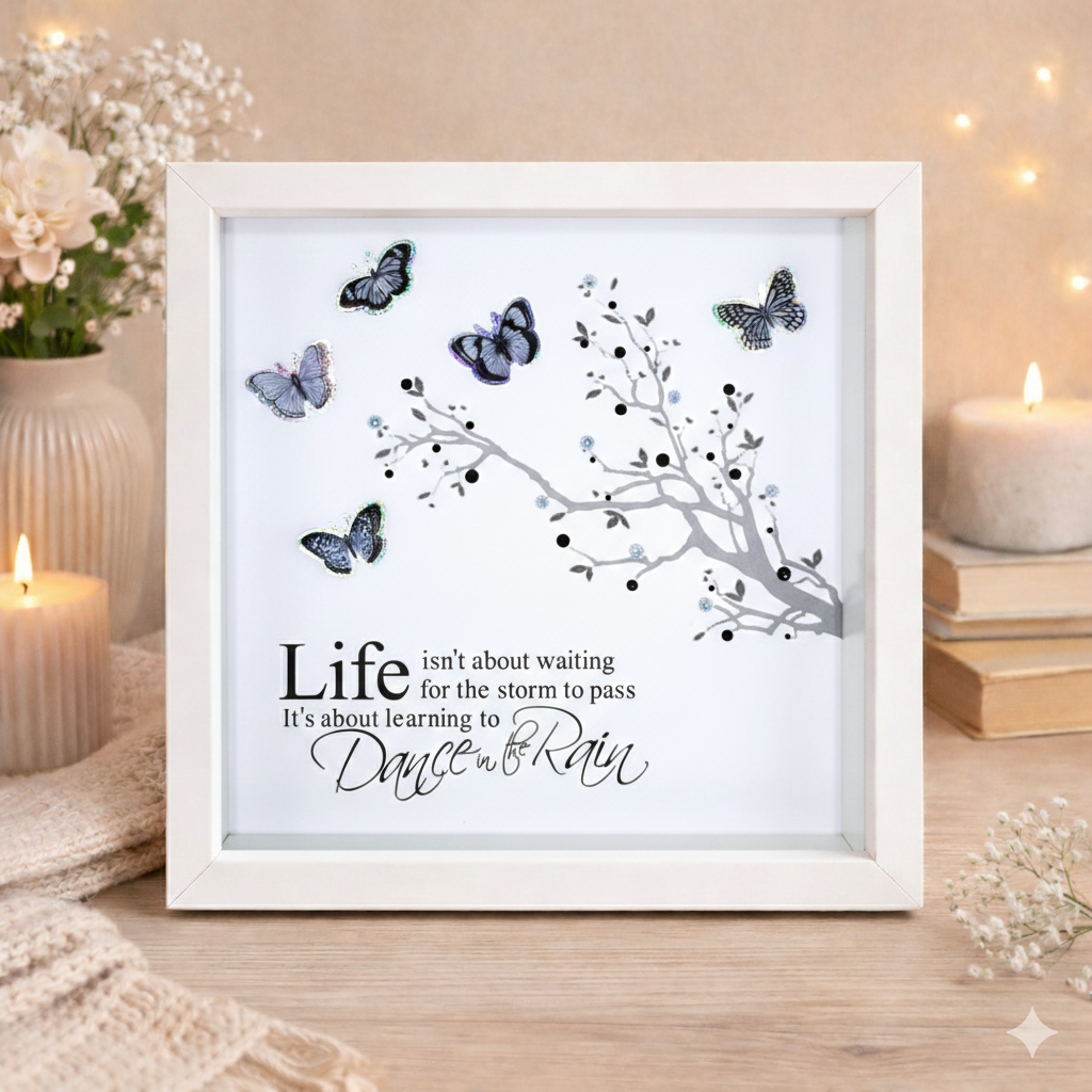 Framed print with butterfly design and motivational quote on a wooden surface with candles and flowers.