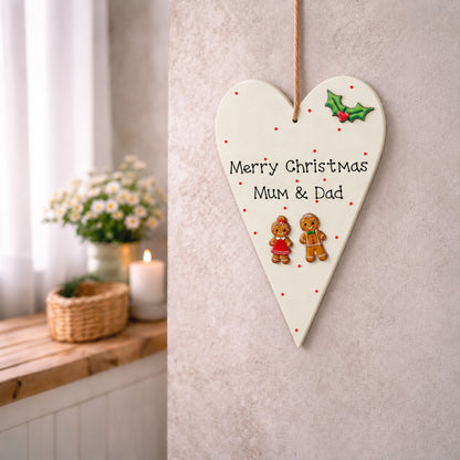 Merry Christmas Mum and Dad wooden heart plaque with gingerbread couple, hanging on a neutral wall