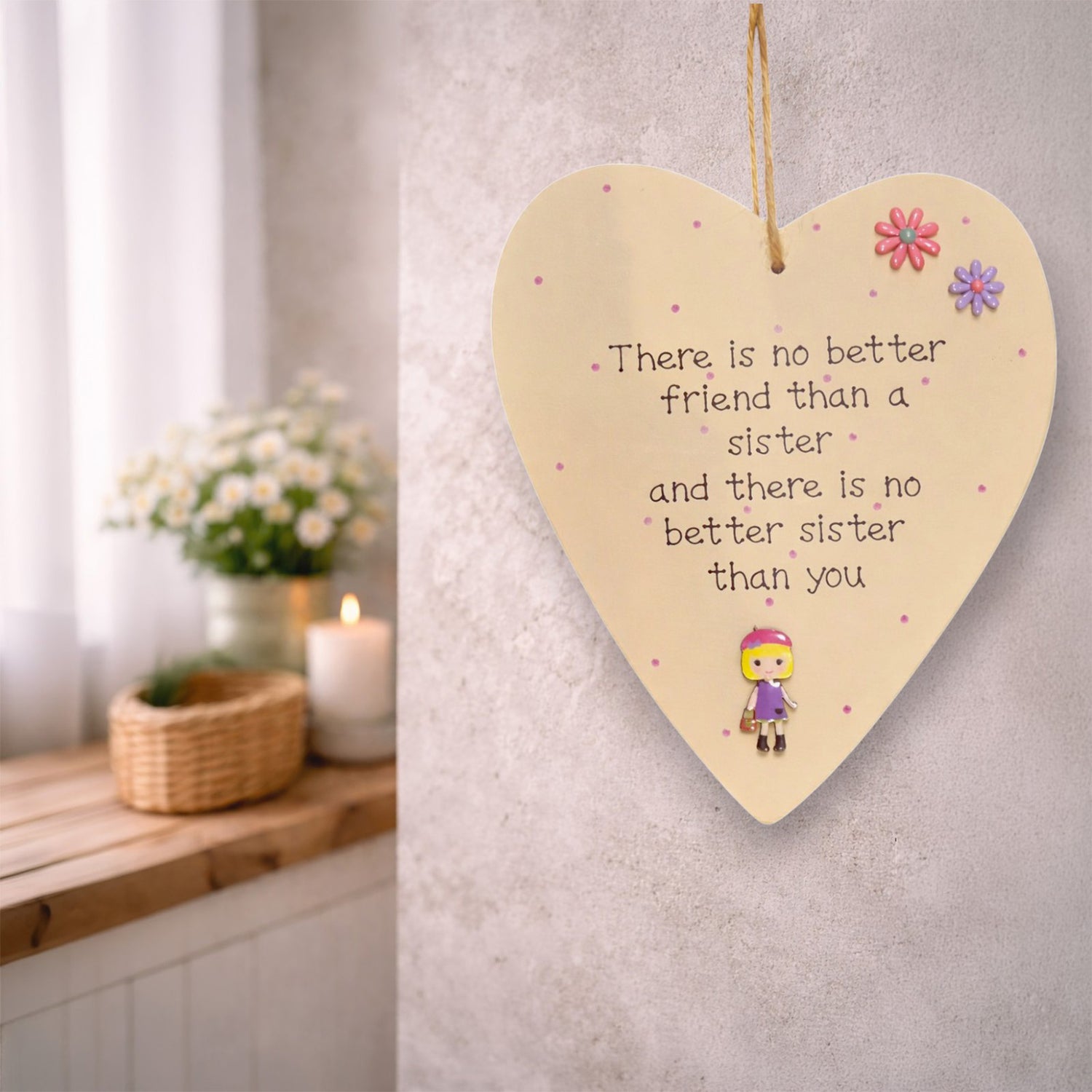 Heart-shaped wooden plaque with a quote no better friend than a sister and there is no better sister than you with buttons and 3d girl, hanging on a wall.