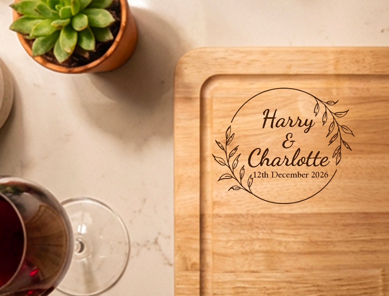 Close-up engraving detail on personalised wooden chopping and serving board, showing a wreath design with names