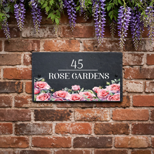 Personalised slate house sign with rose design along the bottom, house number and house name mounted on an exterior wall