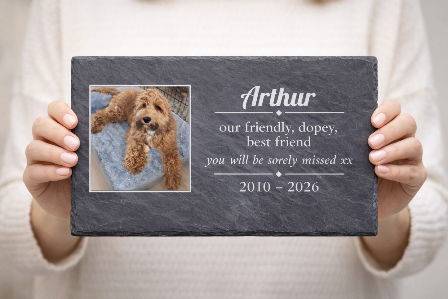 Person holding a pet memorial slate plaque with a photo of a dog and personalised text.