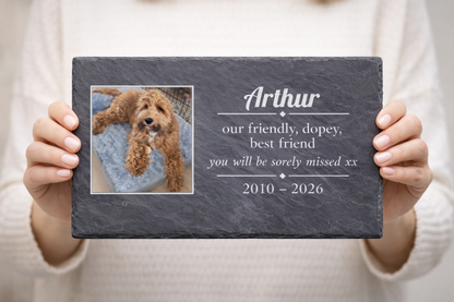 Person holding a pet memorial slate plaque with a photo of a dog and personalised text.
