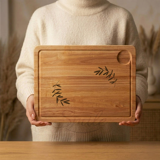 Person holding a wooden cutting board with leaf designs