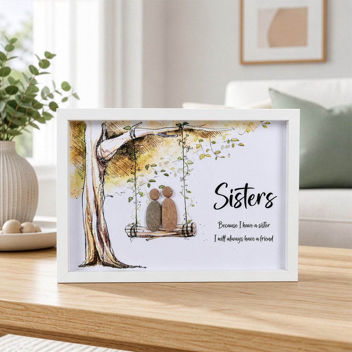 White box frame pebble art showing two stone figures on a tree swing with the quote Sisters Because I have a sister I will always have a friend.