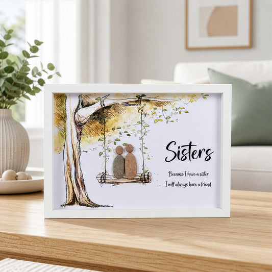 White box frame pebble art showing two stone figures on a tree swing with the quote Sisters Because I have a sister I will always have a friend.